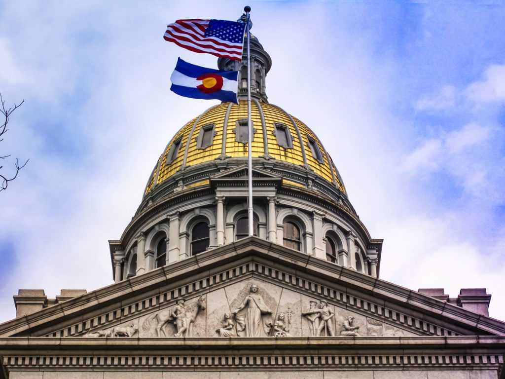 Golden dome of the Colorado state capitol with state and US flags flying